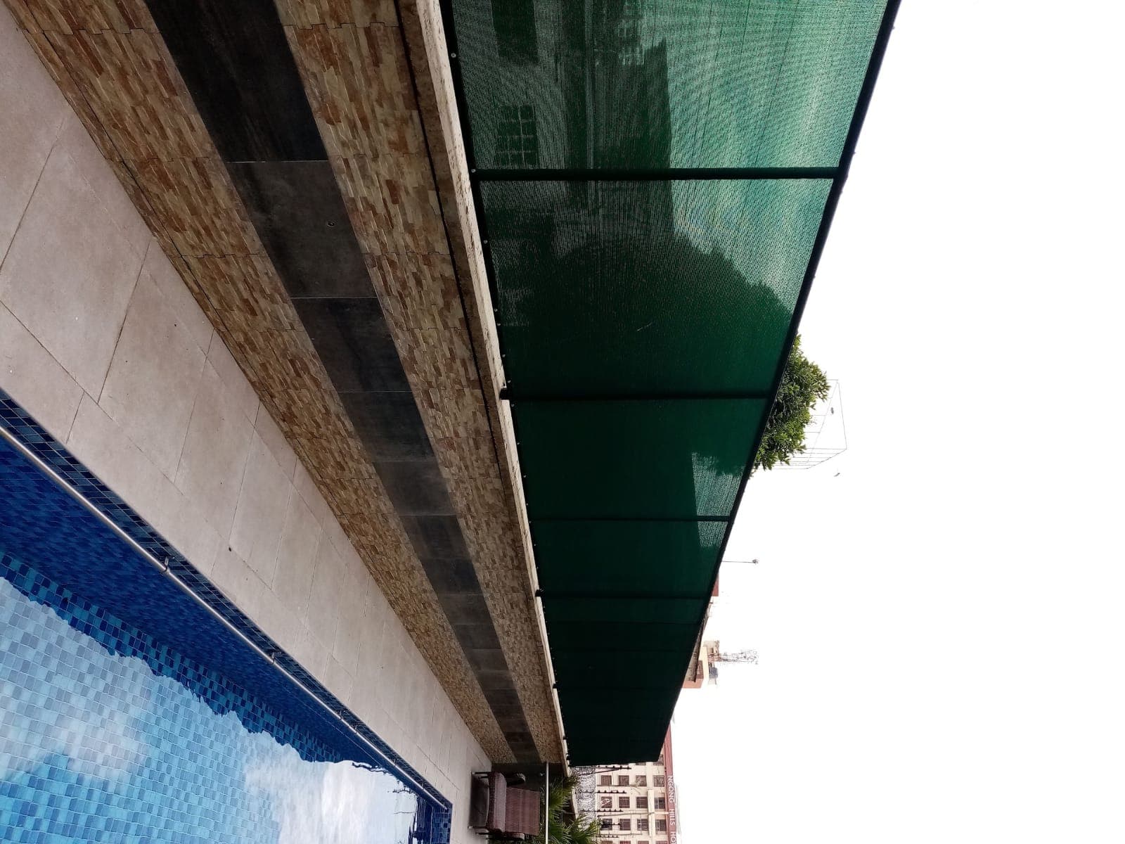 Green HDPE privacy shade net screen installed along a rooftop swimming pool deck in Nyali, Mombasa