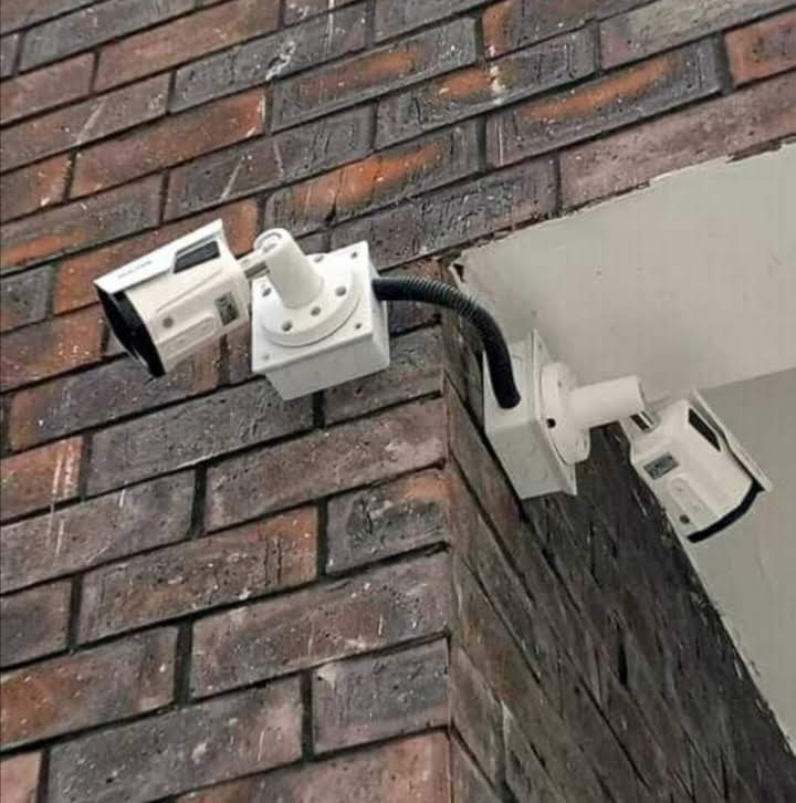 Two bullet CCTV cameras mounted on a shared corner bracket at a brick building corner in Nairobi, covering two approach angles