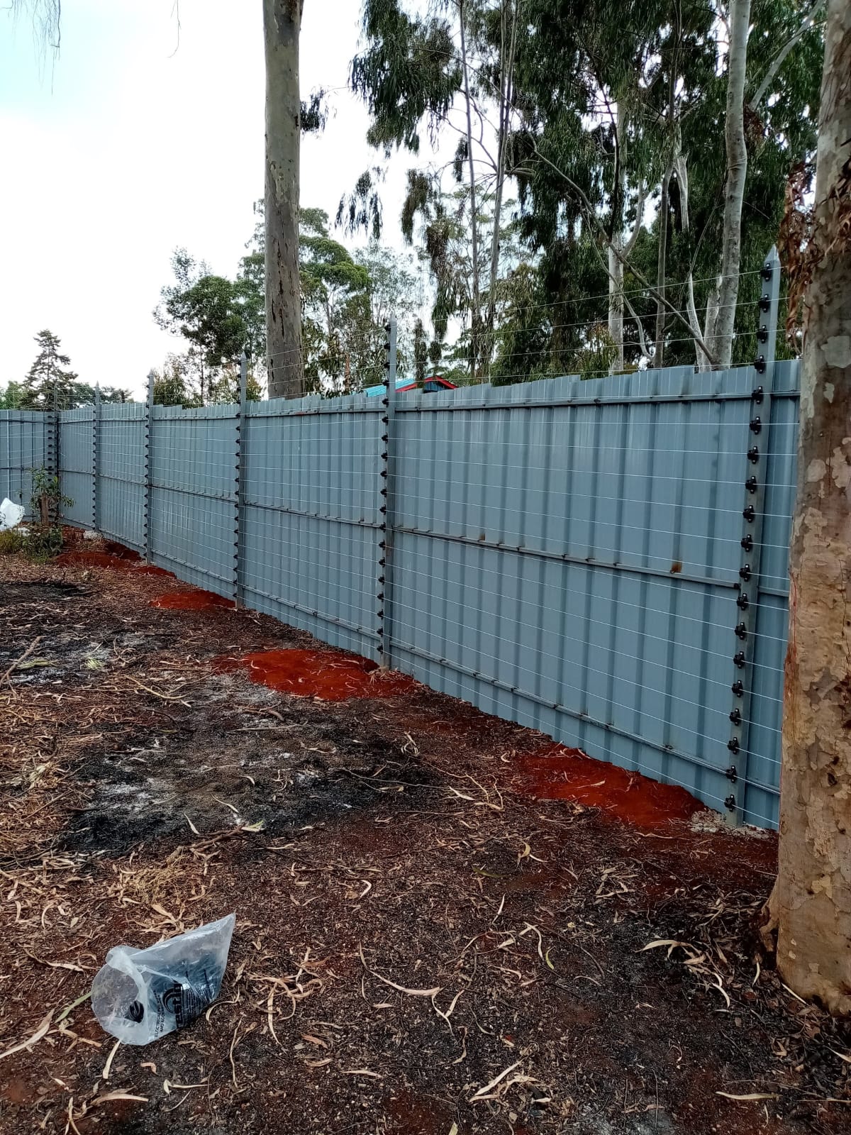 Electric fence wall-top brackets and tensioned wire strands installed along the full run of a Karen perimeter wall