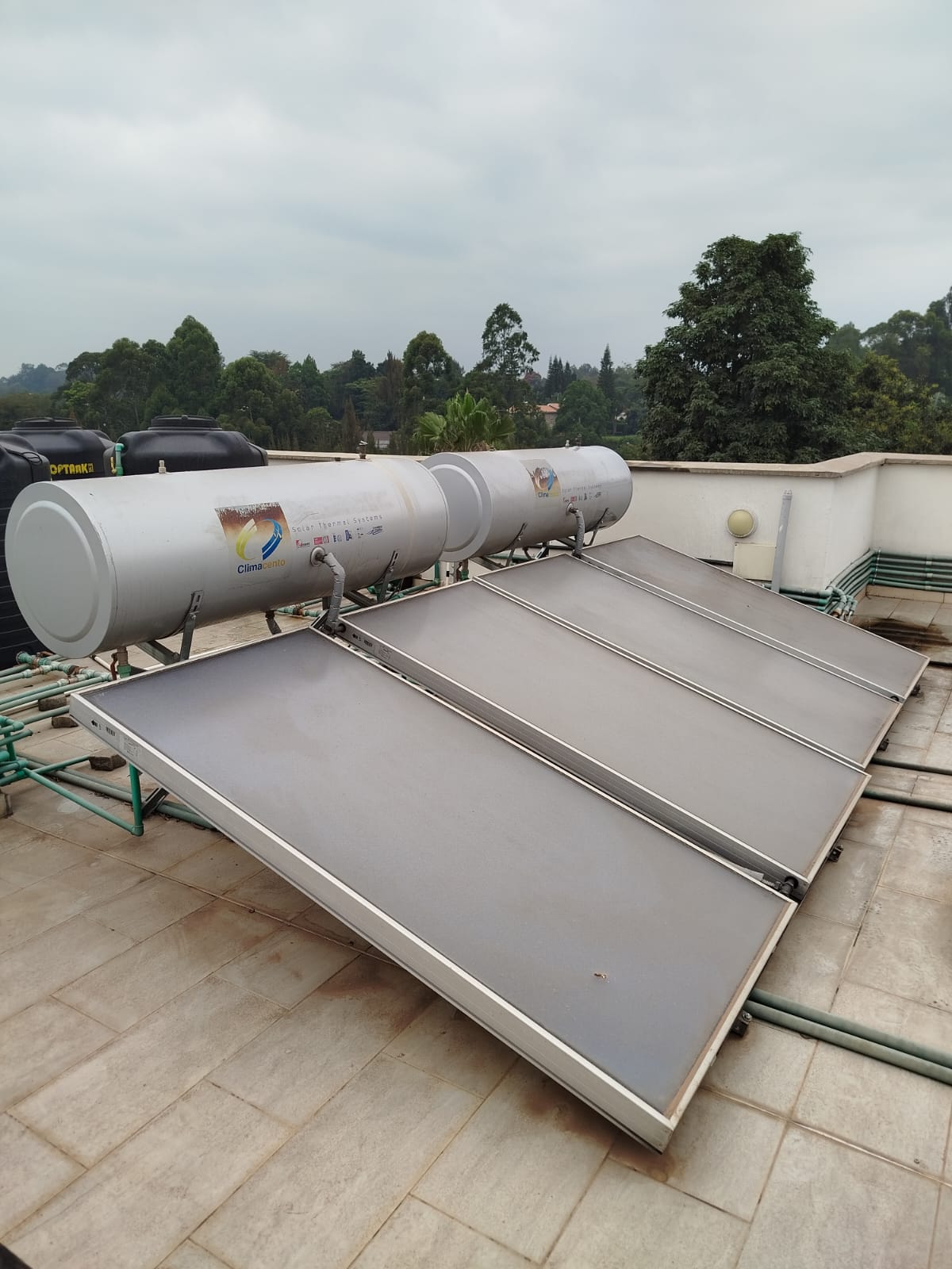 ClimaCento flat-plate solar water heater collectors and storage tanks on a rooftop in Runda, alternate angle showing water storage tanks